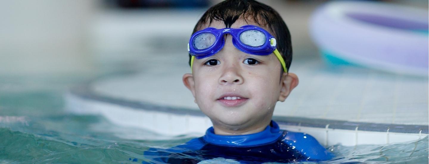 Boy with swim goggles on head in pool