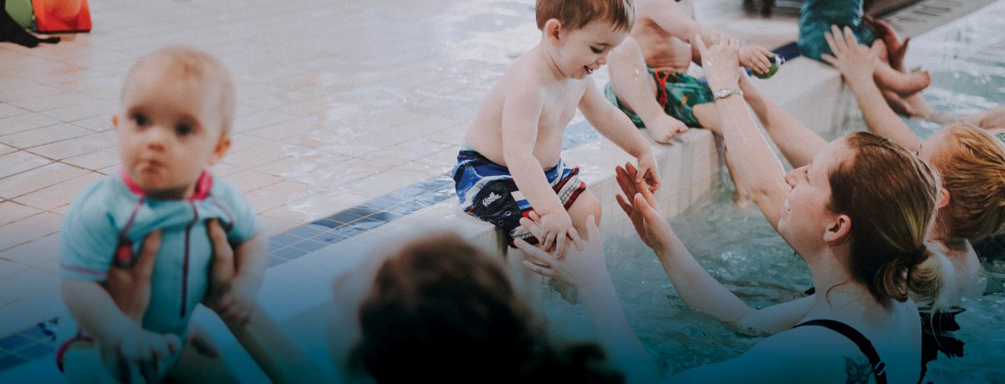 Toddlers learning to swim with parents poolside
