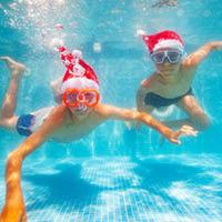 Kids swimming underwater wearing Santa hats
